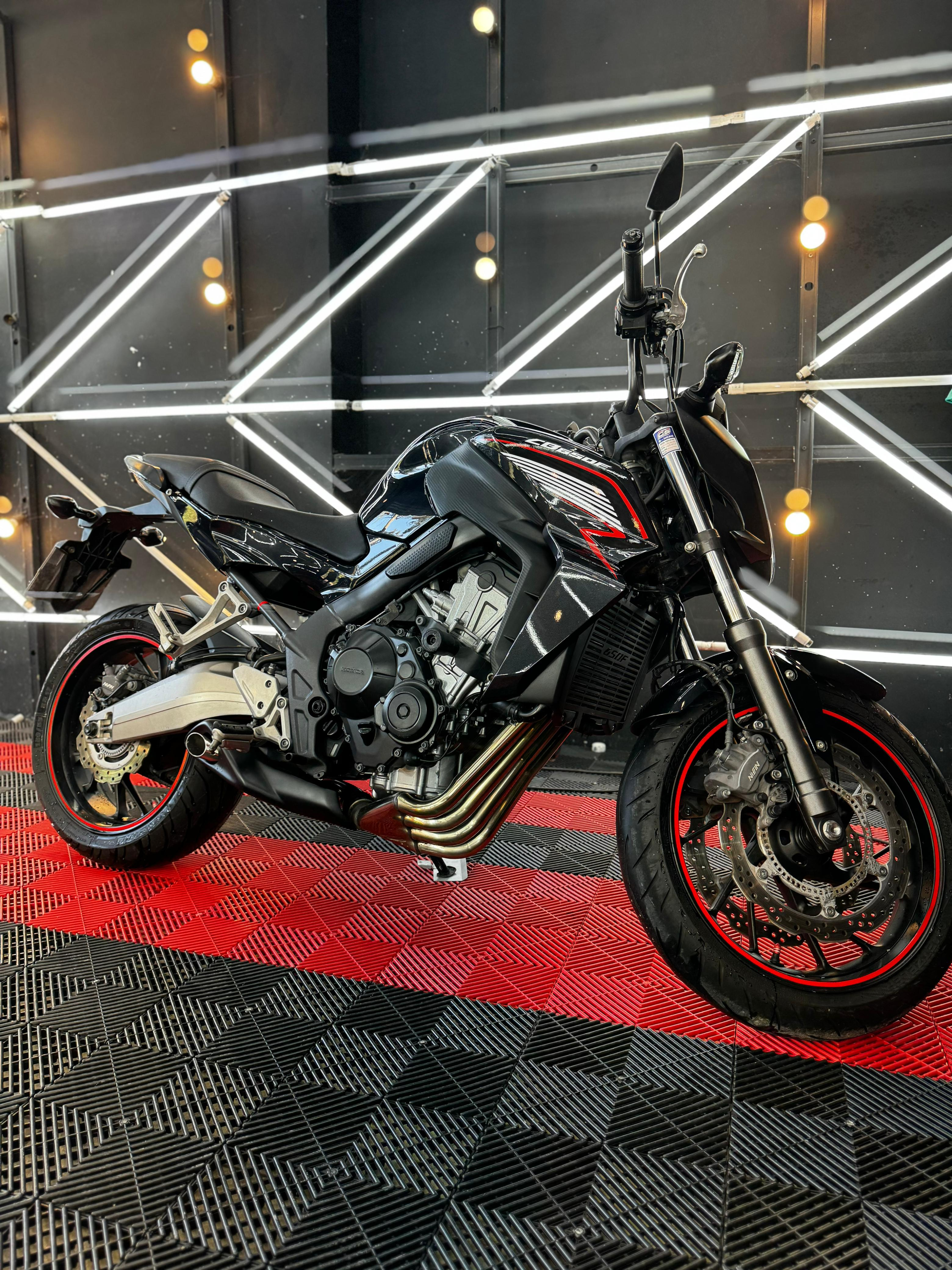 A black car in a showroom with a checkered floor and illuminated wall panels